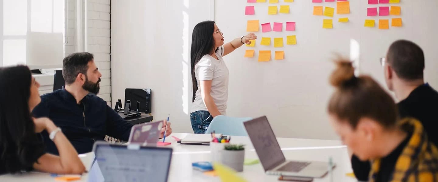 Team collaborating around a whiteboard of sticky notes